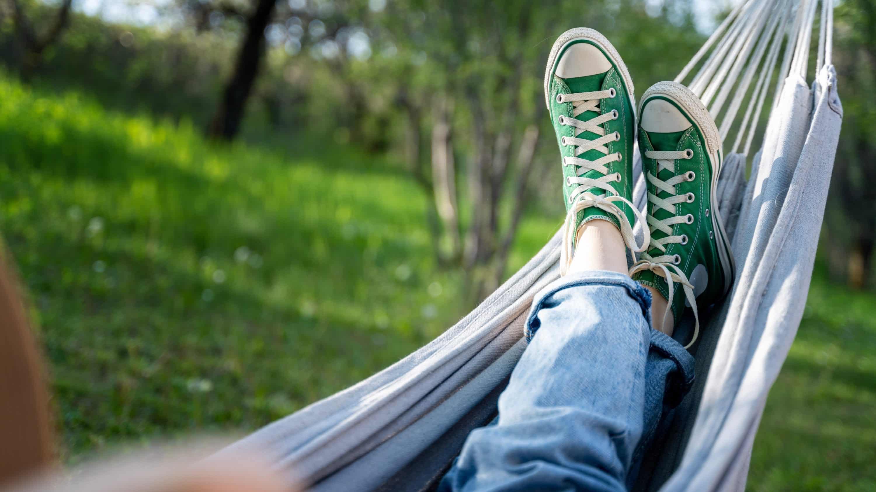 A woman relaxes on a hammock in a park.